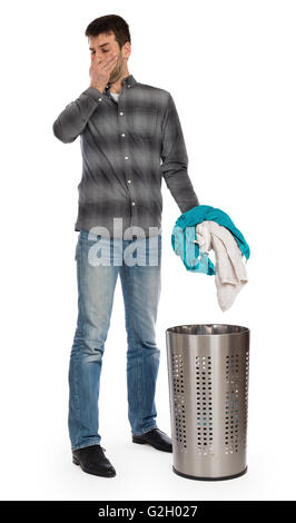 Young man putting a dirty towel in a laundry basket, isolated Stock Photo