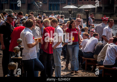 Football fans sat outside pub on riverside in York drinking Stock Photo