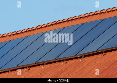 Flat plate solar thermal collectors on a red tile roof Stock Photo