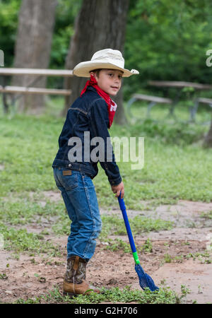 A young boy in cowboy attire collecting frogs and insects at McKinney Falls State Park, Austin, Texas. USA. Stock Photo