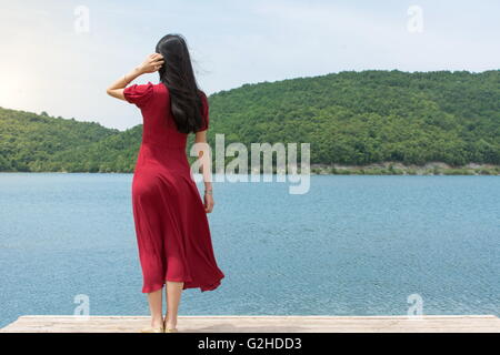 Fashionable woman standing in front of a lake alone Stock Photo