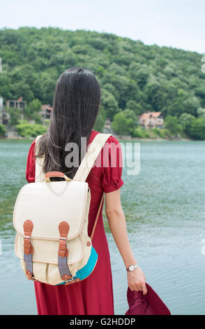 Fashionable woman standing in front of a lake alone Stock Photo