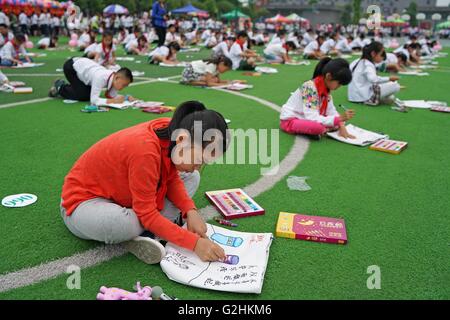 Chongqing. 31st May, 2016. Primary students paint on environment-friendly bags during a painting event to celebrate Children's Day and promote awareness of environment protection in southwest China's Chongqing Municipality, May 31, 2016. © Chen Cheng/Xinhua/Alamy Live News Stock Photo