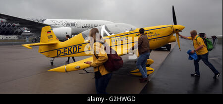 Schoenefeld, Germany. 01st June, 2016. Visitors to the fair push a Mu30 Schlacro into park in the rain at the Berlin Air Show (ILA) in Schoenefeld, Germany, 01 June 2016. The air show at Berlin-Schoenefeld Airport is open from 01 to 04 June 2016. Photo: WOLFGANG KUMM/dpa/Alamy Live News Stock Photo