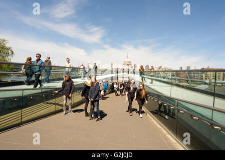 Tourists walking across the famous Millennium bridge in London on May Day Bank Holiday in sunshine Stock Photo