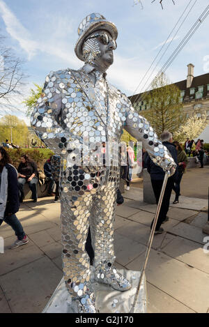 Silver painted statue artist entertaining tourists on the banks of the River Thames in London Stock Photo