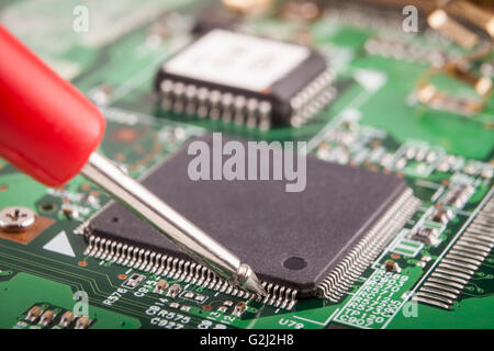 Measuring micro chip with red probe on green circuit board Stock Photo