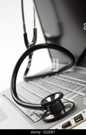 silver laptop diagnosis with black stethoscope crop closeup isolated on white background Stock Photo