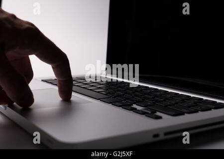 Silver laptop with hand on the trackpad Stock Photo