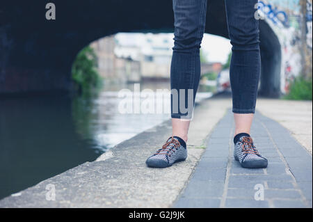 The legs of a young woman as she is standing by a canal Stock Photo