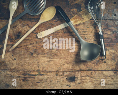 Overhead shot of a selection of spoons and other kitchen utensils on a wooden table Stock Photo