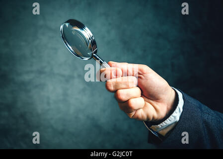 Business analytics and statistics using a magnifying glass, businessman holding vintage tool for optical enlargement Stock Photo