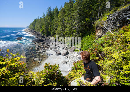 A hiker looks north off a cliff along the West Coast Trail. Pacific Rim National Park Reserve, Vancouver Island, BC, Canada Stock Photo