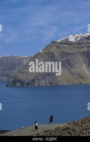 Tourists taken photos of Oia resort from Kameni volcanic islet, in Santorini island, Cyclades, Greece Stock Photo