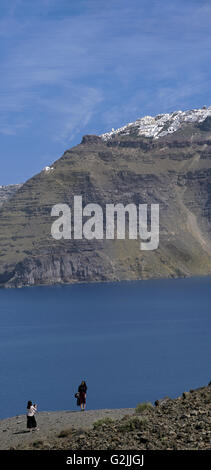 Tourists taken photos of Oia resort from Kameni volcanic islet, in Santorini island, Cyclades, Greece Stock Photo