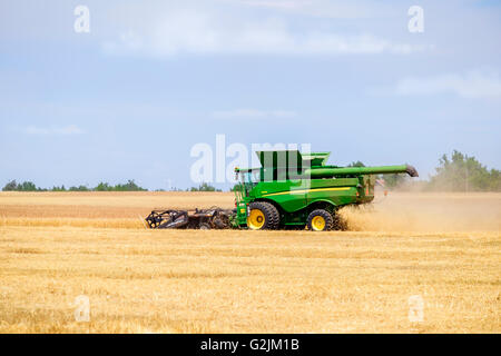 A John Deere combine harvests wheat in Oklahoma, USA.