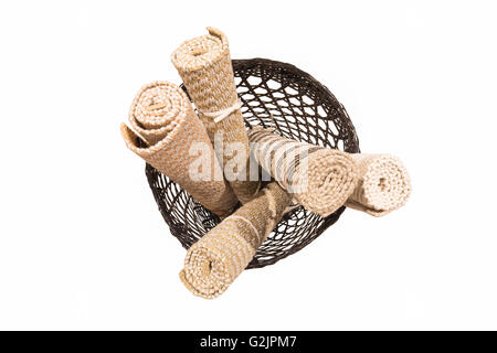 Hand-made short rolled carpets in dark rattan basket isolated on white background Stock Photo