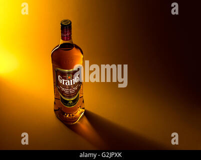 Bottle of whiskey Grant's on a yellowish brown background with light reflections. Stock Photo