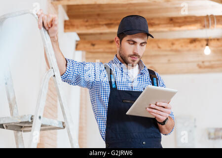 Pensive young worker using pc tablet computer while working indoors Stock Photo