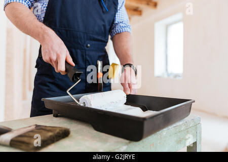 Cropped-image of a builder using paint roller in his work indoors Stock Photo