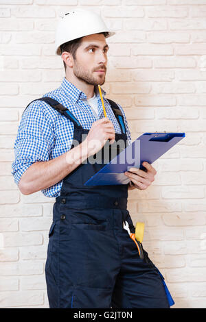 Portrait of a handsome engineer using clipboard to write something while working indoors Stock Photo