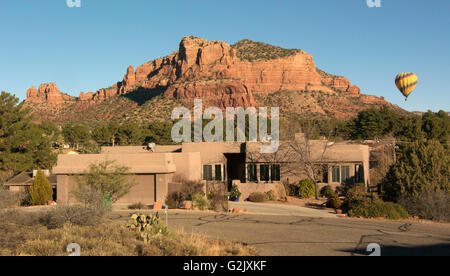 Hot air balloon flying over Castle Rock formation in residential Village of Oak Creek, Sedona, Arizona, North America. Stock Photo