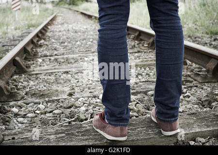Close-Up Of Man's Feet Standing Between Railway Tracks Stock Photo