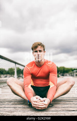 Sportman stretching outside on wooden bridge Stock Photo