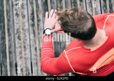 Running man looking sportwatch. Male jogging using smart watch outside Stock Photo
