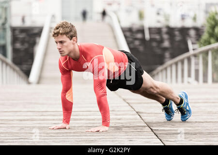 Young athletic man doing push ups. Exercising outdoors. Stock Photo