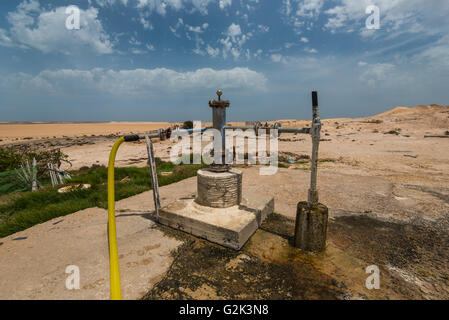 Water well in sandy desert with blue cloudy sky Stock Photo