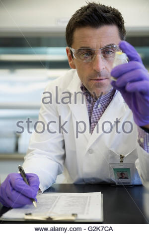 Scientist with specimen taking notes on clipboard in laboratory