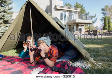 Brothers with binoculars in backyard tent