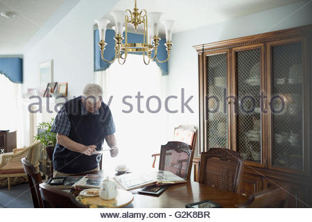 Senior man using digital tablet at dining table with photograph albums