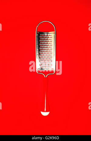 small metal grater on a bright red background Stock Photo