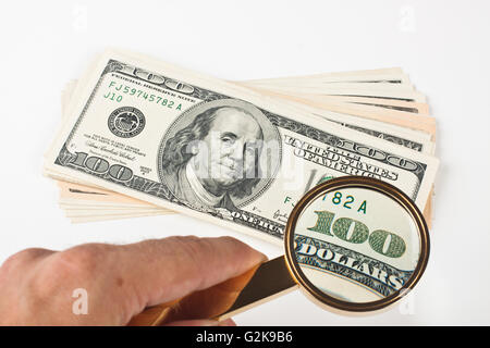 magnifying a hundred dollar bill with golden color loupe Stock Photo