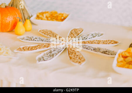 Close up of beatutyfully decorated salty snack to beer: roasted peanuts with small dried fish in fancy white bowls on catering table Stock Photo