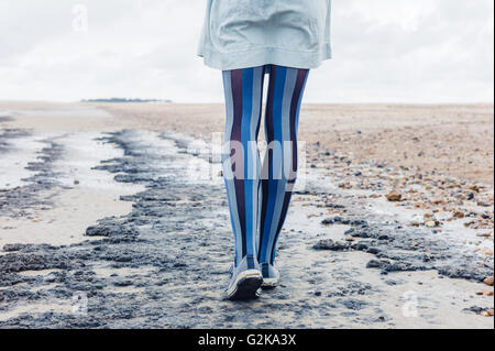 The legs of a young woman as she is walking on the beach Stock Photo