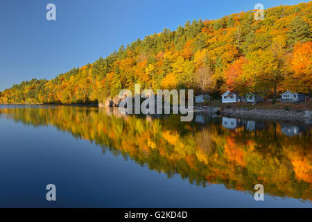 Hiilside of autumn colored trees reflected in Lake St. Nora Near Pine Springs Ontario Canada Stock Photo