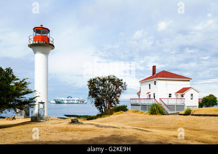 Georgina Point Lighthouse on Mayne Island in British Columbia One of BC Ferries coming out of Active Pass in background. Stock Photo