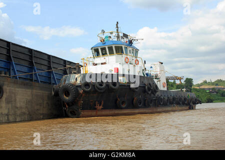 Tug boat on side of the empty barge Stock Photo