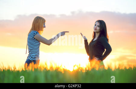 Two girls arguing pointing a finger and ignoring Stock Photo