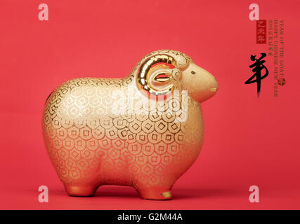 Ceramic goat souvenir on red paper,Chinese calligraphy. word for 'goat', 2015 is year of the goat Stock Photo