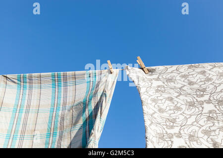 Drying clothes on a sunny day. Wooden pegs holding clothing on a washing line Stock Photo