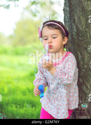 Portrait of funny lovely little girl blowing soap bubbles Stock Photo