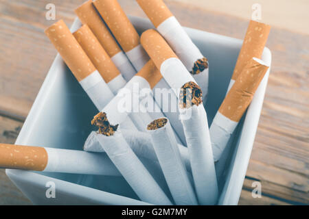 Quit Smoking - Broken unsmoked cigarettes in a white ashtray with blueish filter Stock Photo