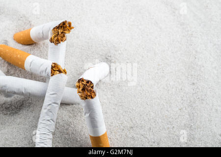 Quit Smoking - Broken unsmoked cigarettes in sand with copyspace Stock Photo