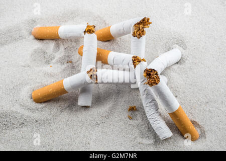 Quit Smoking - Broken unsmoked cigarettes in sand Stock Photo