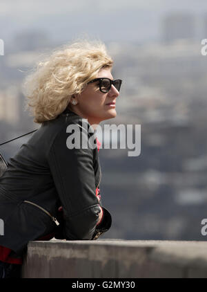 Beautiful blonde woman with curly hair is looking into the distance Stock Photo
