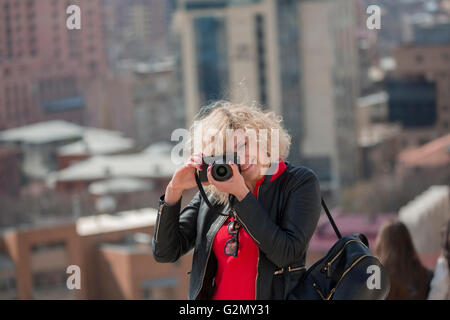 Beautiful blonde woman with curly hair is making photo Stock Photo
